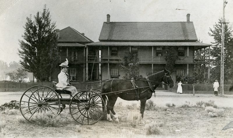 KMA Photograph 30: The original Kamloops hospital on Lorne Street and 3rd Avenue, with addition, showing Matron Eleanor Potter in a buggy in the foreground. A nurse and cook are shown in the background. 1890.