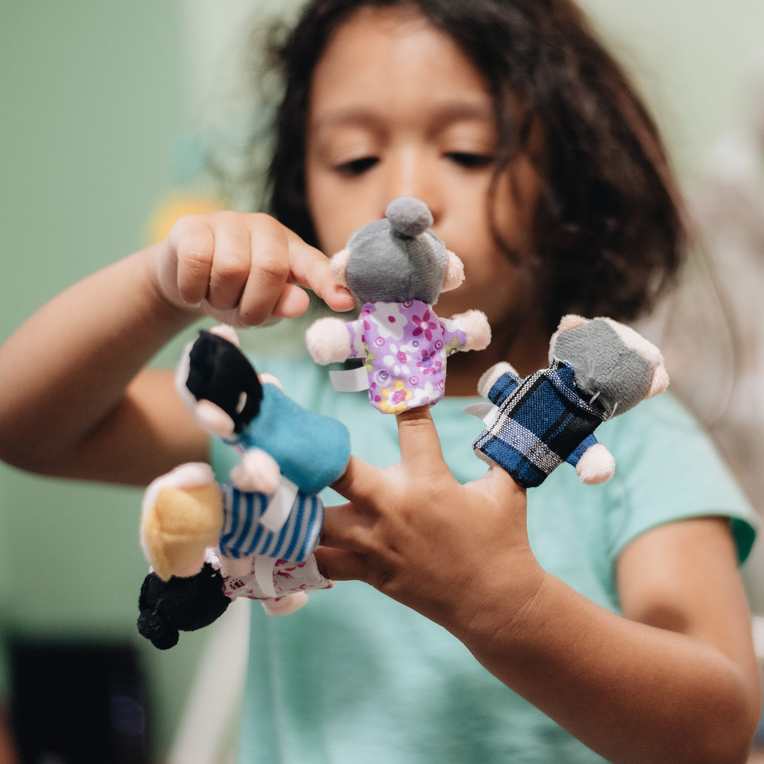 Young kid playing with small finger puppets on her fingers.