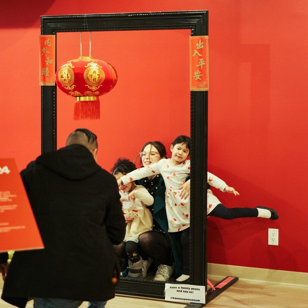 A mother and two kids pose in a black frame as the dad takes a photos.