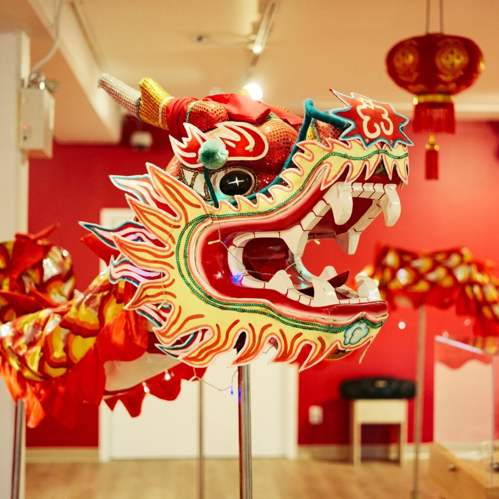 The head of a Chinese dancing dragon is on steaks in the center of a red room.